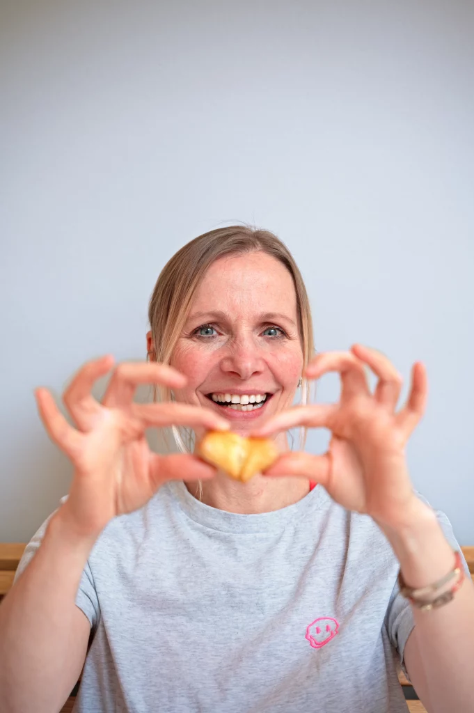 Dr. Susanne Güntzer bricht eine Süßigkeit mit ihren Händen in zwei Teilen und lächelt dabei.
