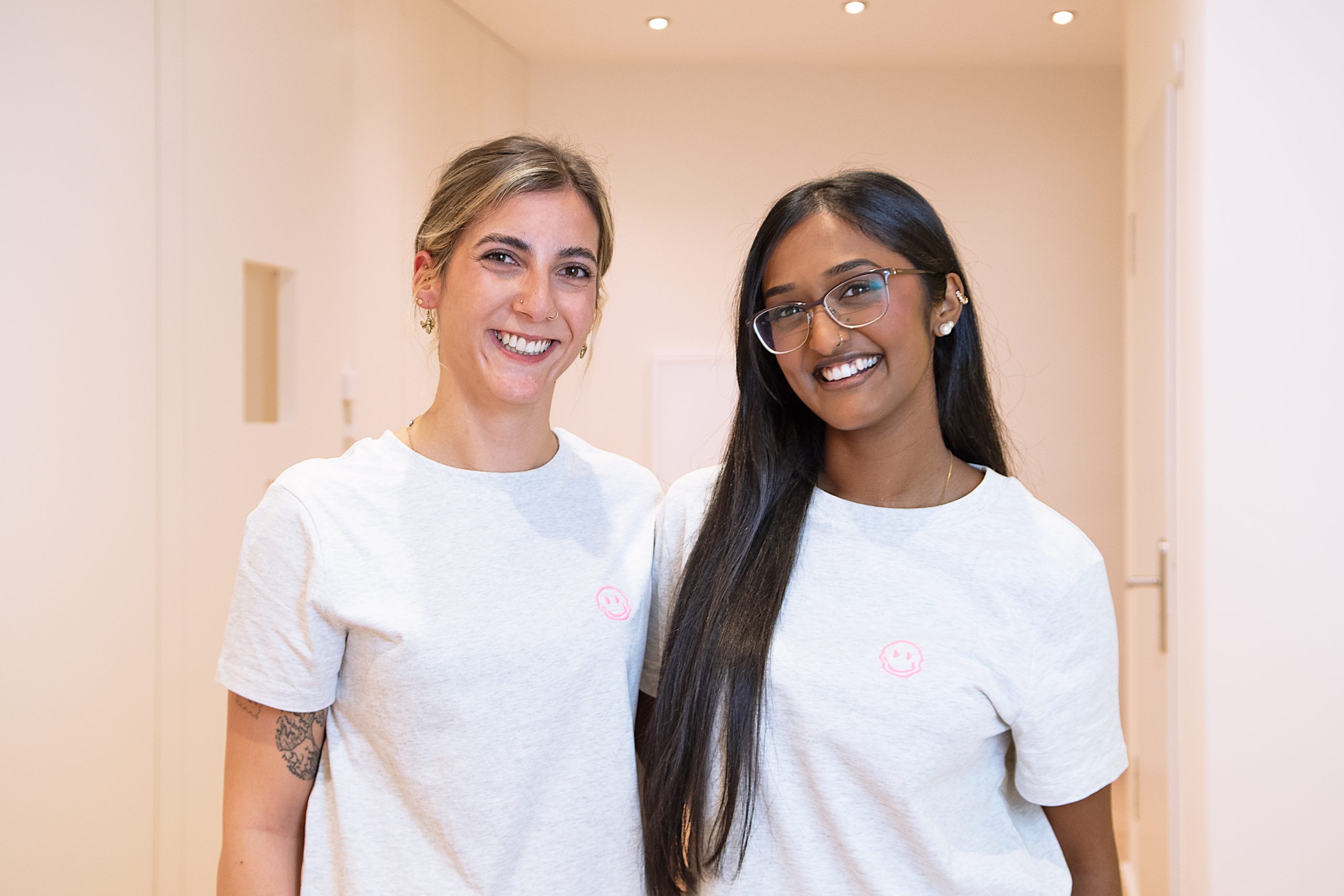 Zwei fröhliche Mitarbeiterinnen lächeln.