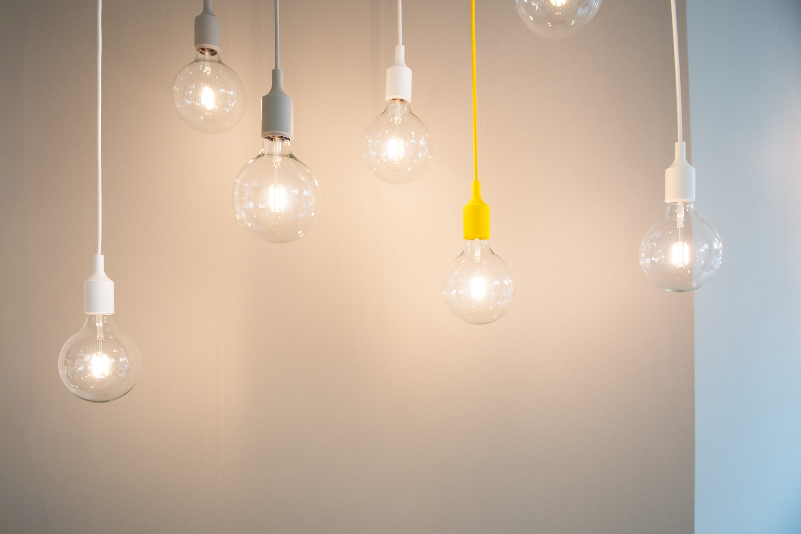 Mehrere Glühbirnen hängen von der Decke und beleuchten eine Wand.