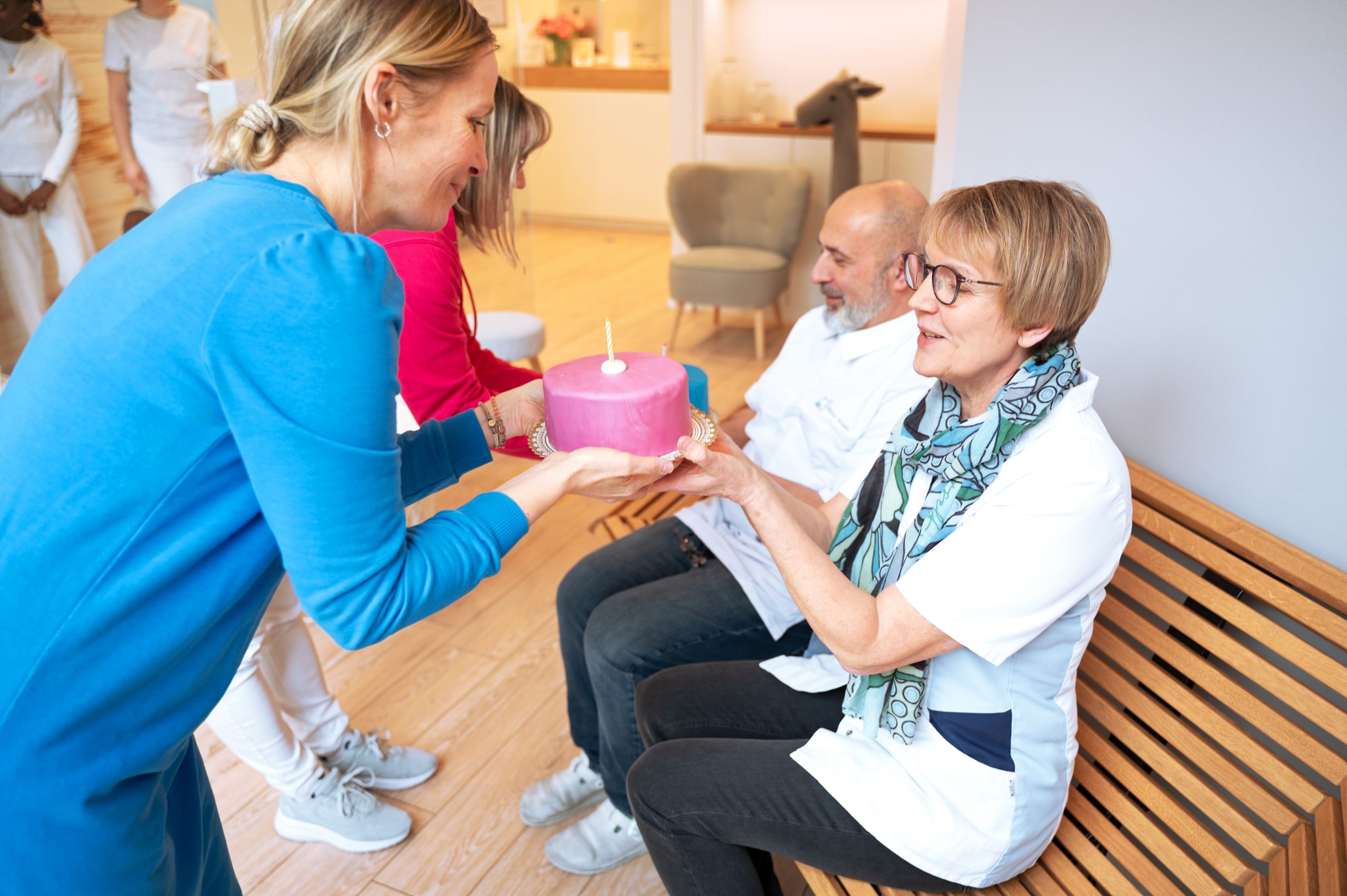 Das Bild zeigt wie Dr. Susanne Güntzer zwei Mitarbeitern ihre Kuchen zum Jubiläum überreicht