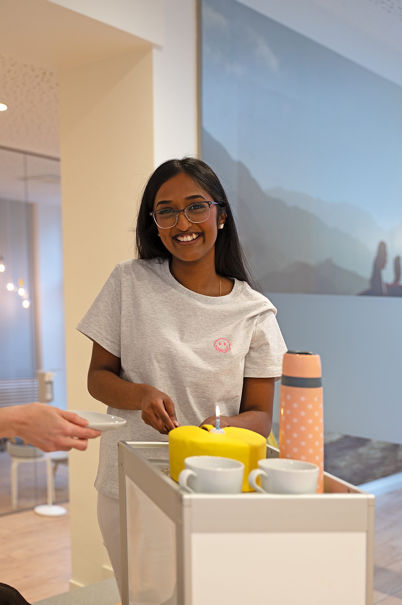 Ein Bild das den Kuchen zum Jubiläum eines Mitarbeiters zeigt. Eine Mitarbeiterin schneidet den Kuchen an.